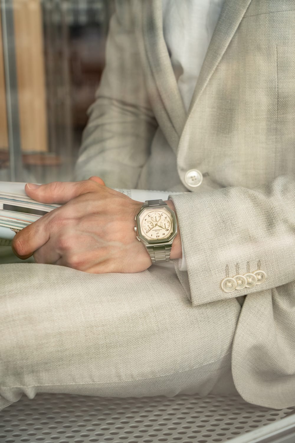 1904 Chronograph by AV86 luxury timepiece with angular case, sapphire crystal, chronograph dial, and metal bracelet strap worn with beige suit