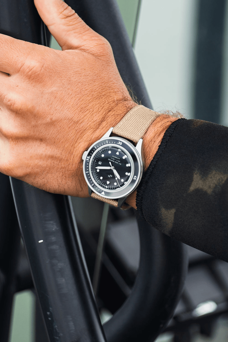 1956 Marine Automatic by AV86 vintage-inspired diver with sapphire crystal, black dial, and beige fabric strap on wrist