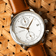 1834 Chronograph by AV86 luxury chronograph with sapphire crystal, white dial, steel case, and brown leather strap on wicker background