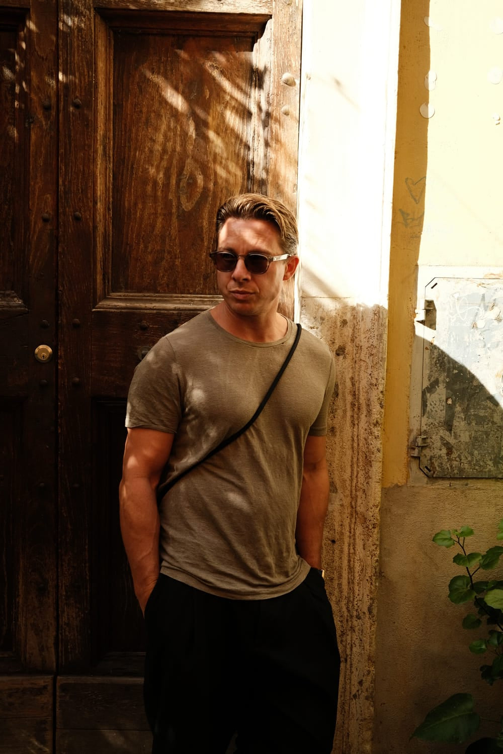 Man wearing sunglasses and a casual outfit standing by a wooden door, showcasing the 1954 Amalfi Mechanical, Steel / Off White by AV86.