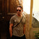 Man in casual minimalist outfit wearing 1954 Amalfi Mechanical, Gold / Midnight Blue by AV86 standing by rustic wooden door in warm sunlight