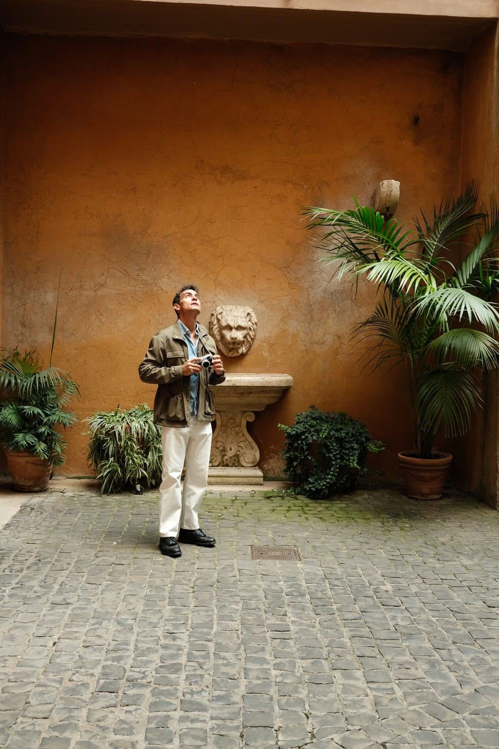 Man wearing 1954 Amalfi Mechanical, Steel / Off White watch by AV86 in a courtyard with plants and rustic wall background