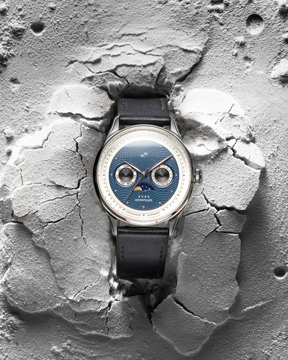 AV86 moonphase watch with vintage-inspired dial, sapphire crystal, chronograph subdials, and black leather strap on textured surface
