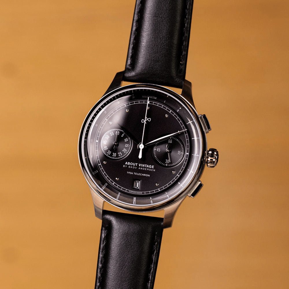 1934 Telechron by AV86 features a vintage-inspired chronograph with a black dial, dual subdials, date window, sapphire crystal, polished steel case, and black leather strap, exemplifying Nordic minimalism and horological excellence.