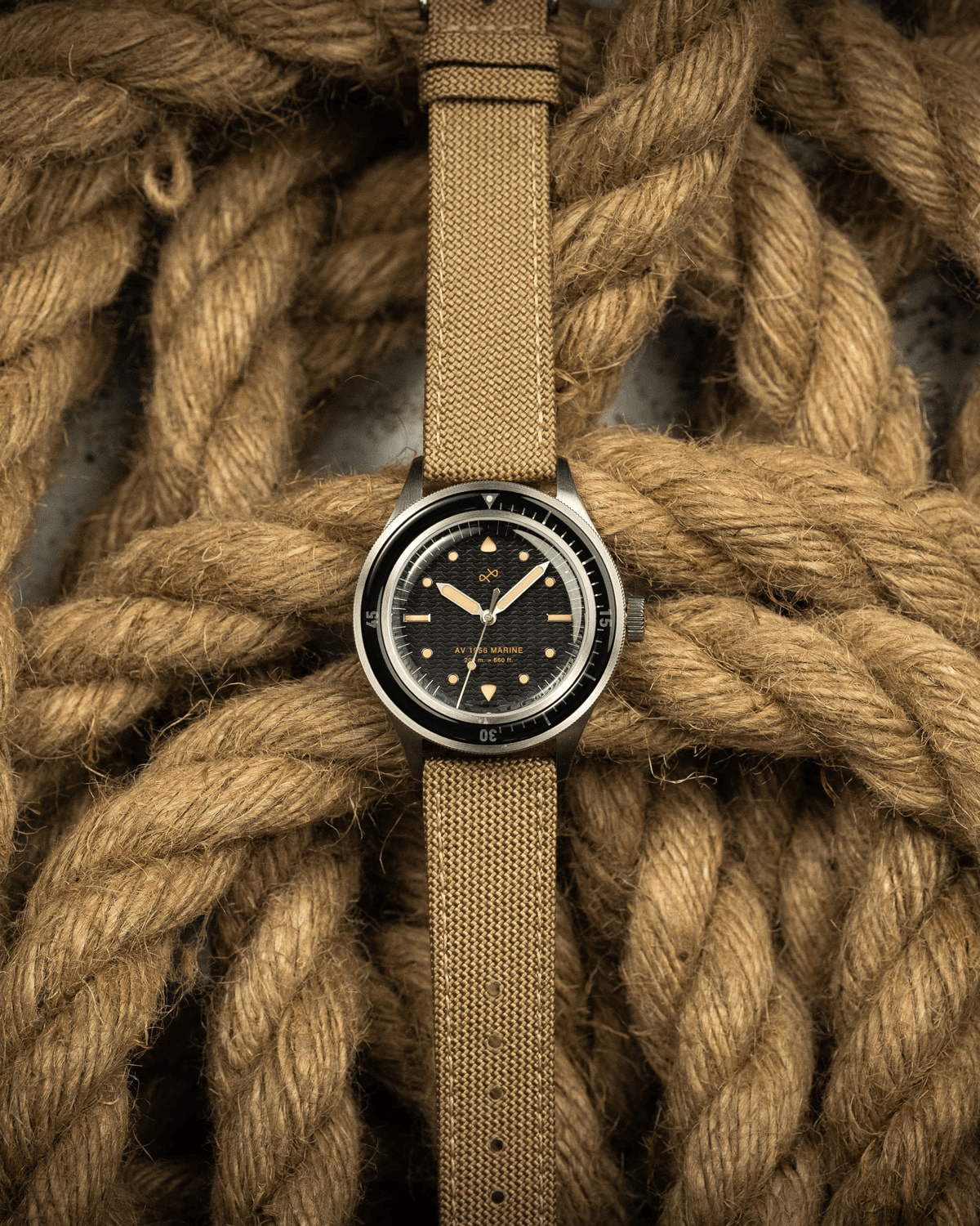 1956 Marine by AV86 vintage-inspired diver watch with acrylic bezel, luminous markers, and textured fabric strap on nautical rope background