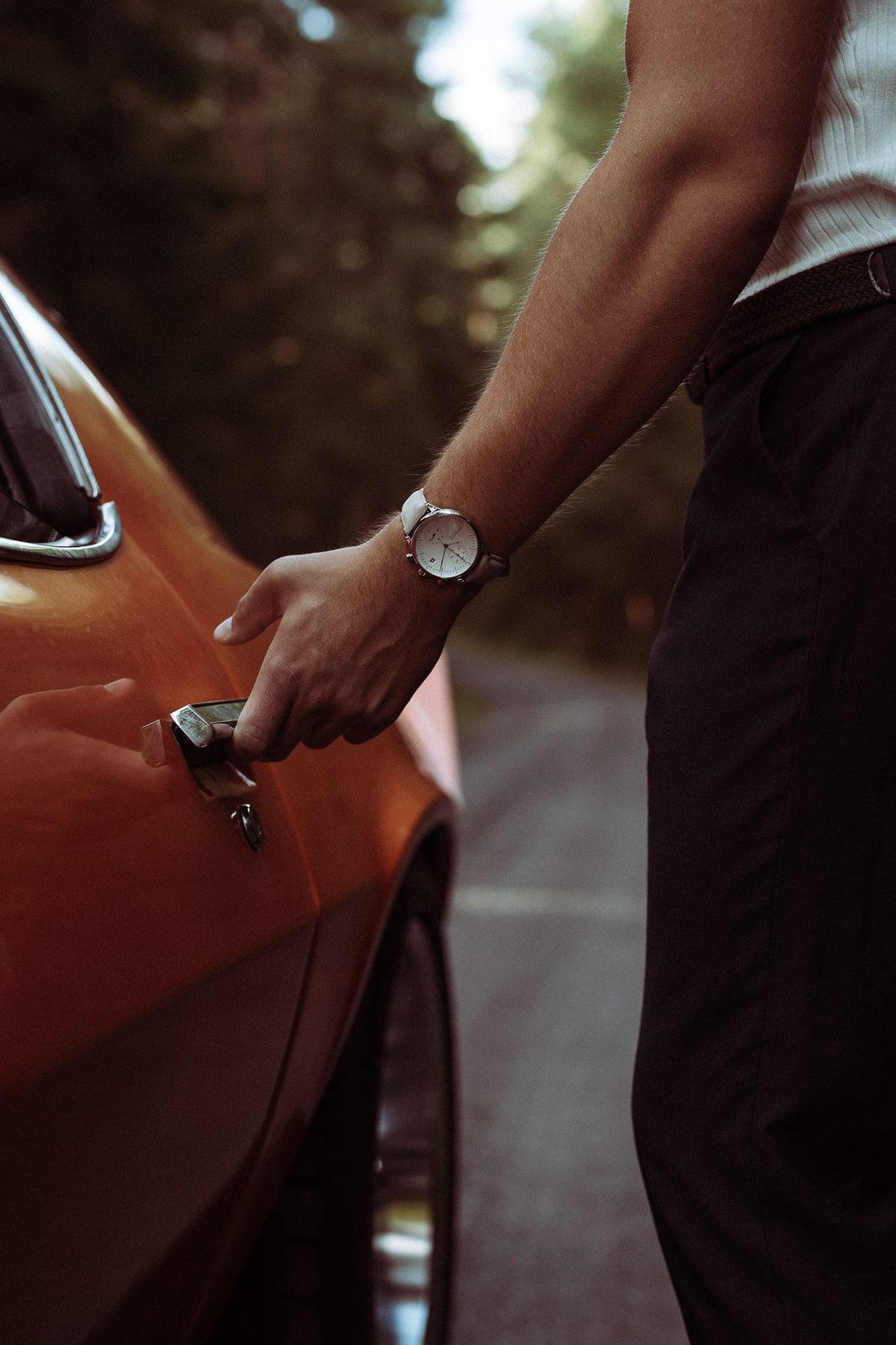 AV86 vintage-inspired dress watch with a pale dial and dark leather strap worn by a man opening an orange car door outdoors