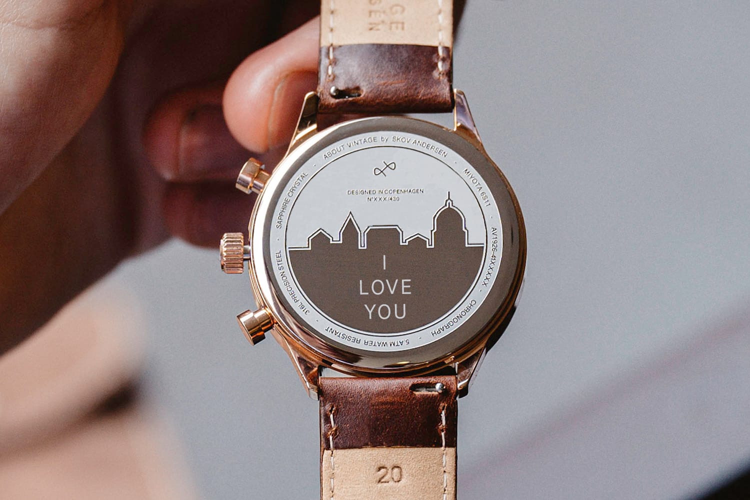 AV86 chronograph with engraving on case back featuring city skyline and "LOVE YOU" message, brown leather strap