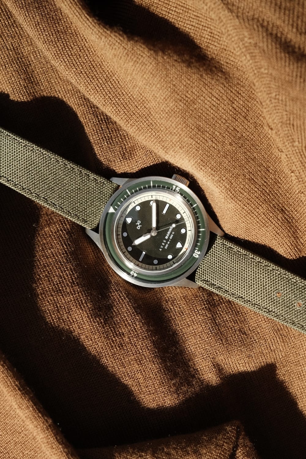 1956 Marine by AV86 vintage-inspired diver with sapphire crystal, unidirectional bezel, and durable fabric strap on textured fabric background