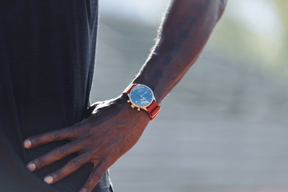 1815 Justin Gatlin, Gold / Blue Turtle by AV86 luxury chronograph with sapphire crystal and orange leather strap on wrist outdoors